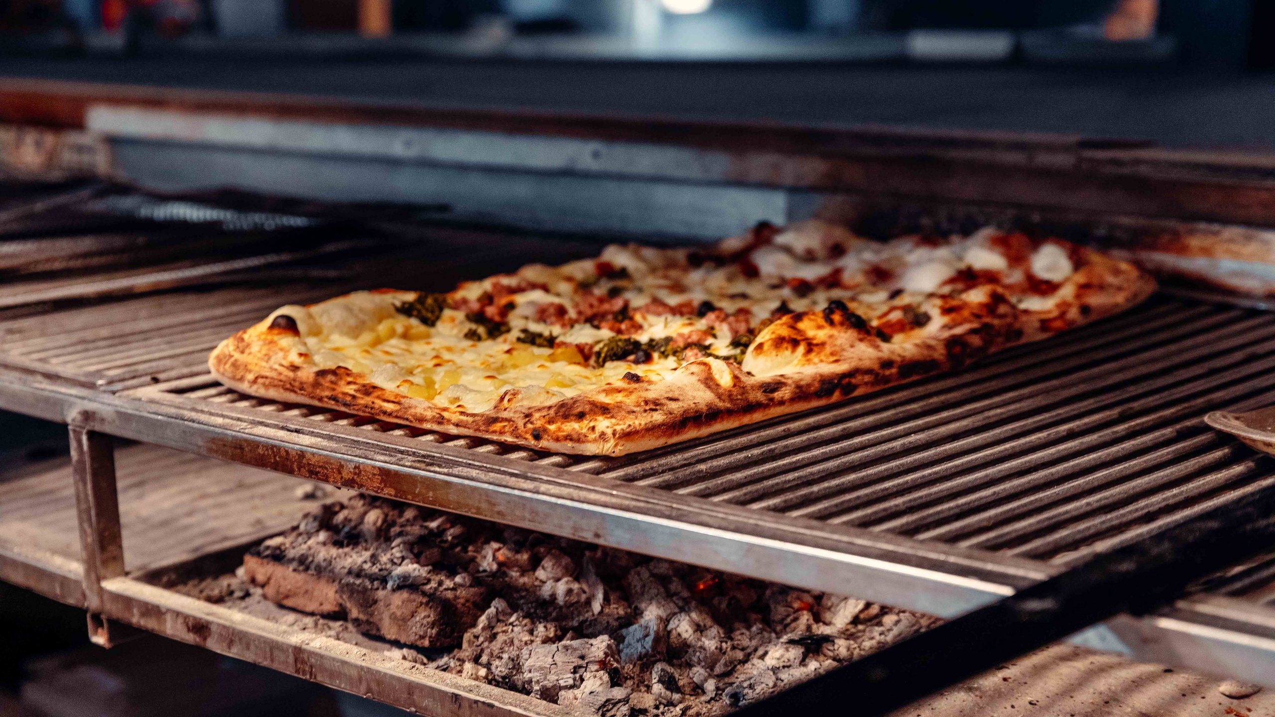 La pizza di Pulcinè sulla griglia, con la brace accesa sotto