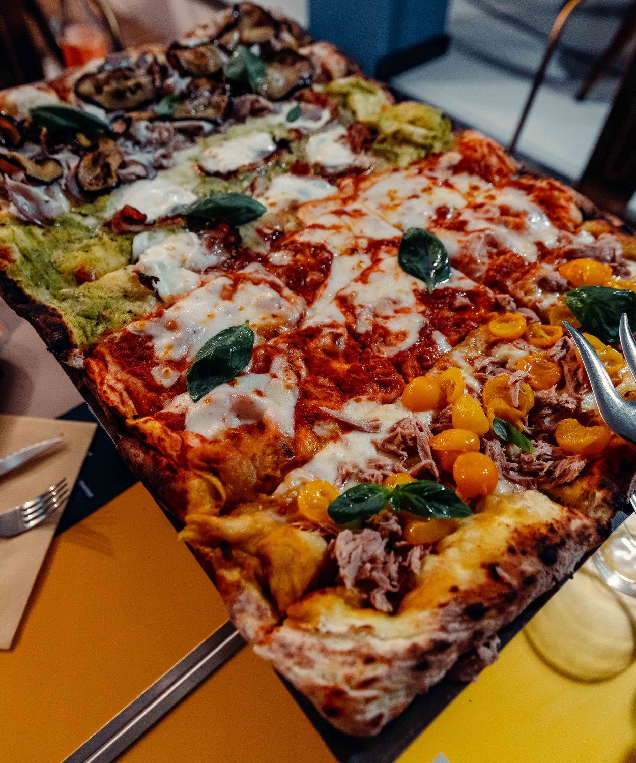 La Brace Intera 60×40 di Pulcinè servita al tavolo, con quattro gusti diversi sulla stessa pizza