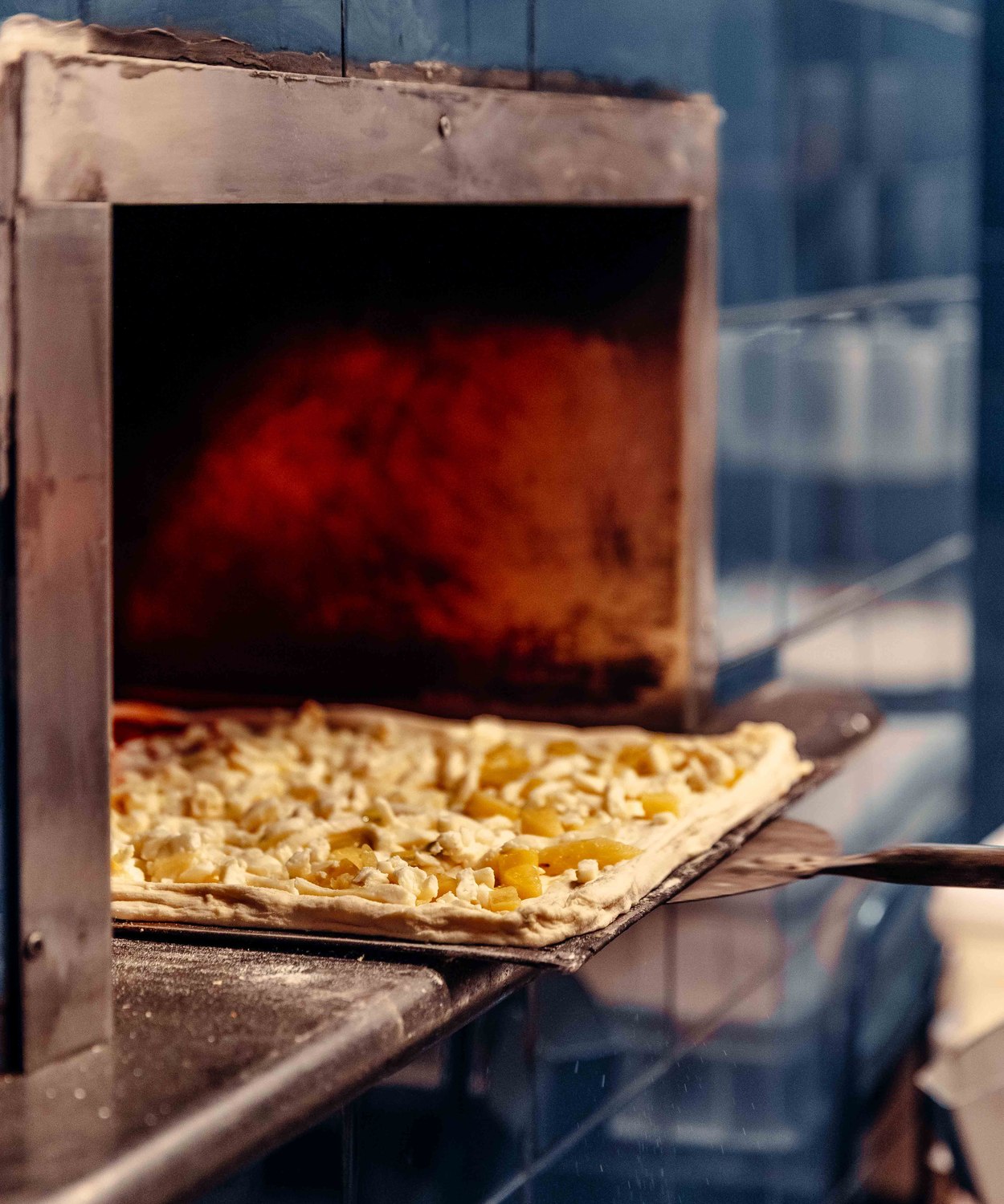 La pizza di Pulcinè stesa a mano sulla griglia e condita, pronta per il forno
